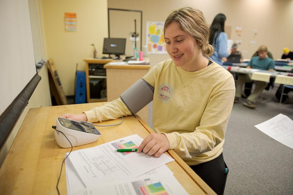 A student takes a blood pressure test in the Burkhiser Complex